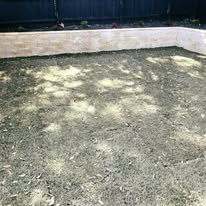 Brick retaining wall enclosing a freshly prepared garden bed